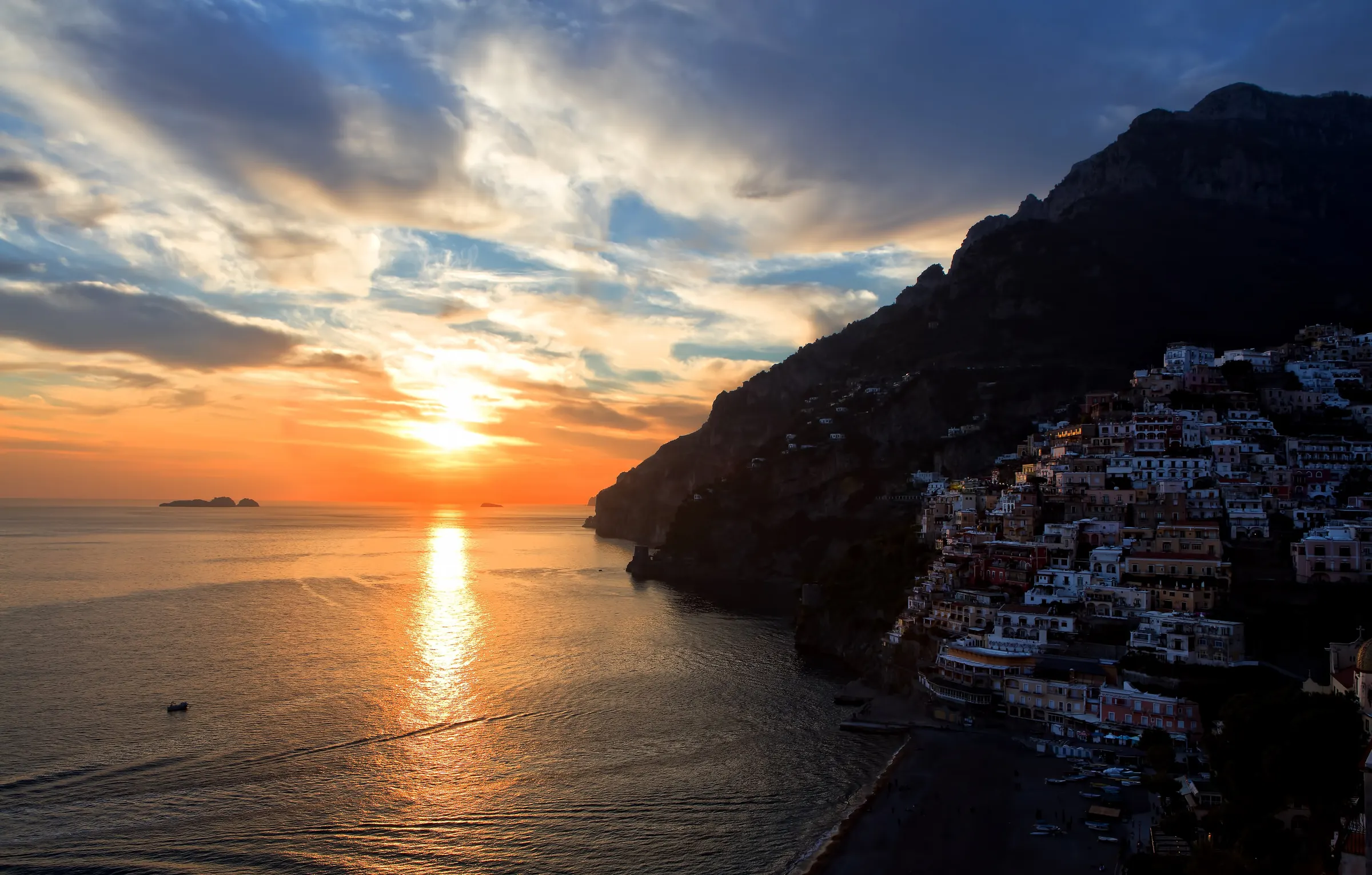 Positano and the Amalfi Coast at sunset, the sun setting over a calm sea
